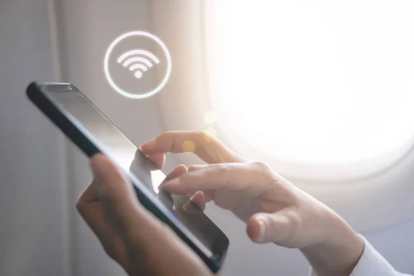 Женщина рука с помощью смартфона с иконкой Wi-Fi на фоне самолета . — стоковое фото