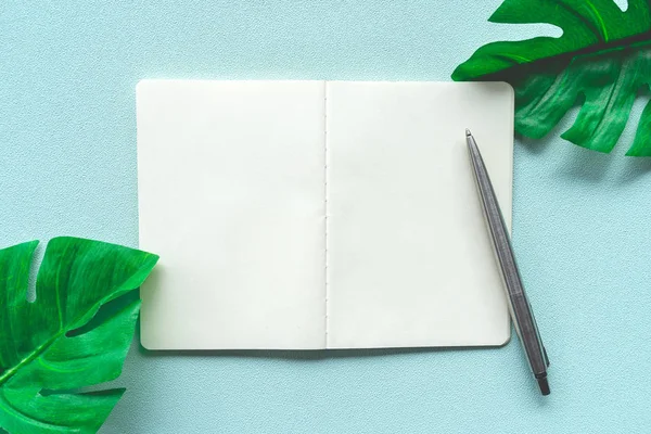 Weißes Notizbuch und Kugelschreiber mit tropischem Blatt als Rahmen. — Stockfoto