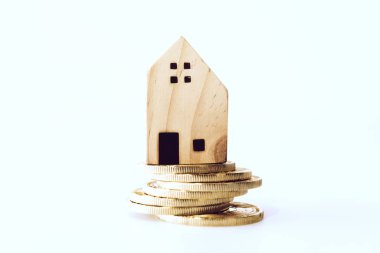 Mini house model on gold coin with clean white copyspace background. Business invest property saving.