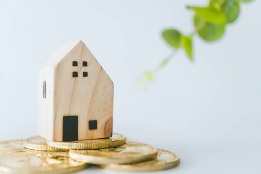 Mini house model on gold coin with clean white copyspace background. Business invest property saving.