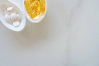 Beyaz kaşıkta doğal vitamin takviyesinin üst görüntüsü mermer dokuların çerçevesi olarak. Sağlıklı beslenme yaşam tarzı eğilimi.