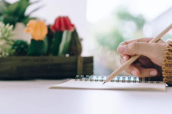 Kvinna handen skriva ner i vit PM anteckningsbok för att ta en anteckning att inte glömma, att göra lista eller planera för arbete i framtiden på arbetsbordet. — Stockfoto