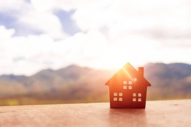 Zemine ya da ahşap tahta kaplı, güneş ışığı yeşil bokeh arka planlı minik ev modelini kapattım. Deam 'in yaşam ve yatırım konsepti için kendine ait bir mülkü var..