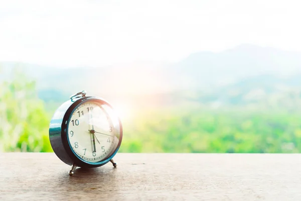 自然のボケ山の背景とテーブルの上に目覚まし時計の選択的な焦点 人生の概念と朝の人の時間 — ストック写真