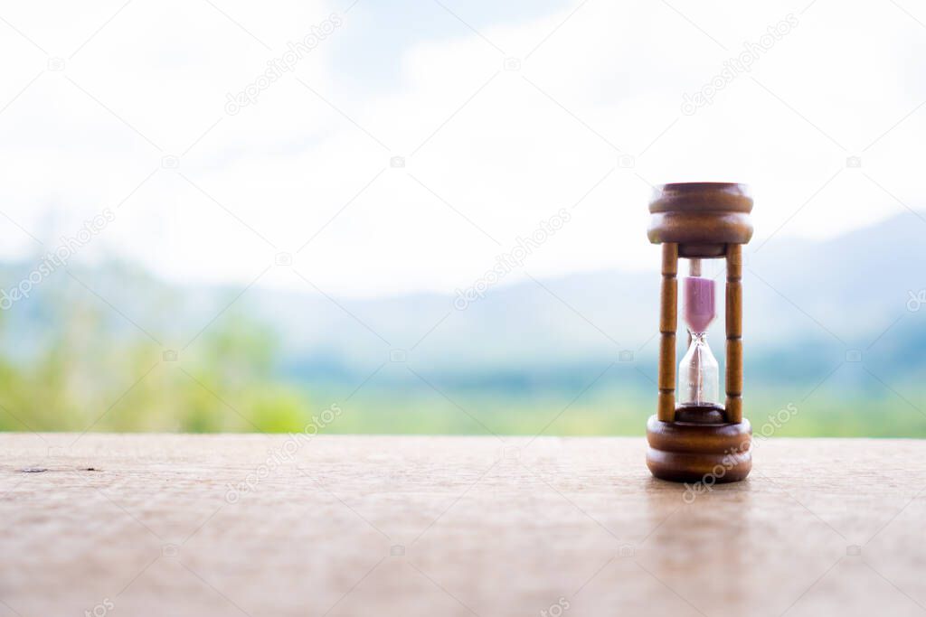 Small vintage hourglass show time is flowing never return with nature background.