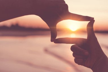 Kadın ellerinin seçici odak noktası dağda gün doğumuyla birlikte kare kare hareketler yapması, kadın güneşin doğuşunu ya da dışarıda gün ışığını yakalaması. Gelecek planlama kavramı.