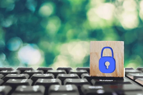 Closed up lock icon as security show on wood cube on computer keyboard. Protect safety on network activity business technology concept.