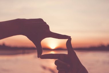 Kadın ellerinin seçici odak noktası dağda gün doğumuyla birlikte kare kare hareketler yapması, kadın güneşin doğuşunu ya da dışarıda gün ışığını yakalaması. Gelecek planlama kavramı.