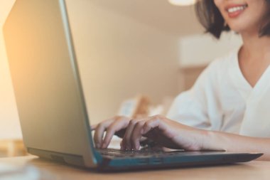 Çalışma masasında çalışmak için bilgisayarını kullanırken mutlu kadın gülümsüyor. Geçmişi temiz. İş, finans, ticaret hisseleri ve sosyal ağ kavramı.
