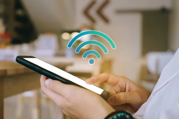 Açık alan arka planında wifi ikonu olan akıllı telefon kullanan bir kadın. İş iletişimi sosyal ağ kavramı.
