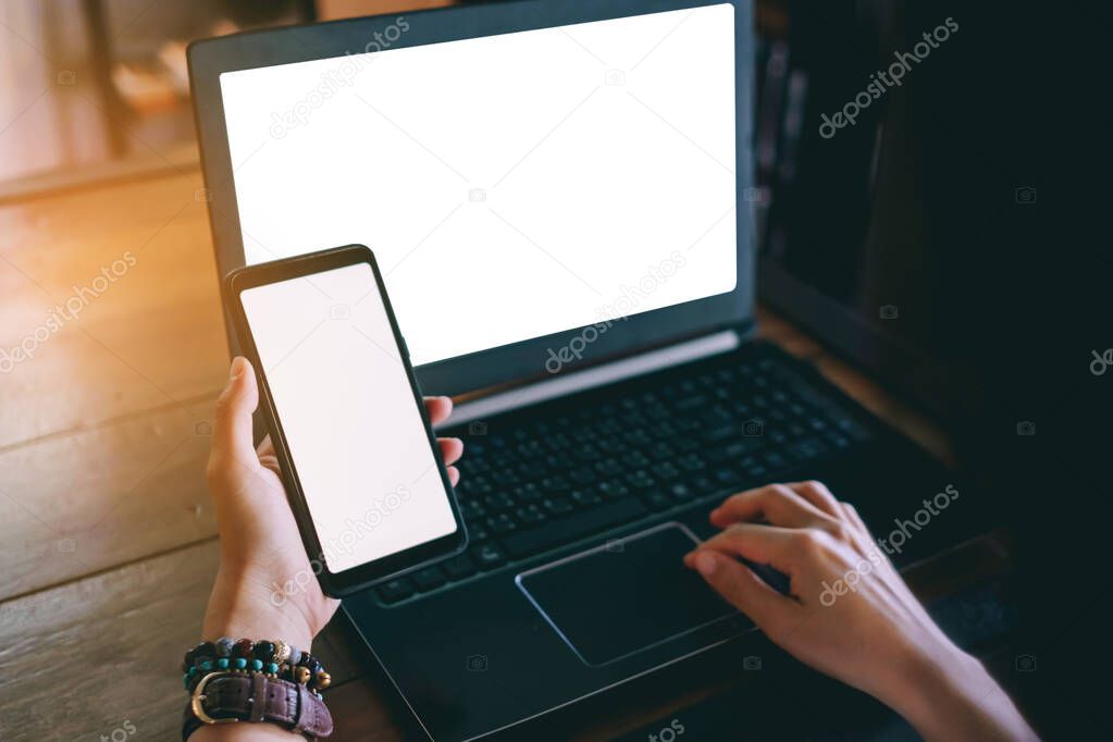 Woman hand using laptop or smartphone to work study on work desk with clean nature background background. Business, financial, trade stock maket and social network concept.