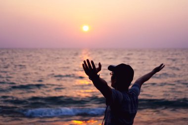İnsanoğlu gökyüzü özgürlük kavramına yükselir. Günbatımı gökyüzü ve yaz plajı arka planı ile..