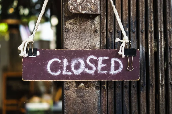 A Sign board of sorry we are closed hang on door of business shop with nature green background