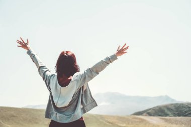 Kadın gökyüzü özgürlük kavramına el kaldırır mavi gökyüzü ve yaz doğa dağ arka planıyla.