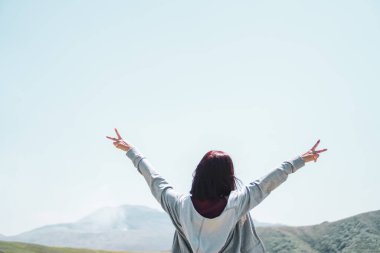 Kadın gökyüzü özgürlük kavramına el kaldırır mavi gökyüzü ve yaz doğa dağ arka planıyla.