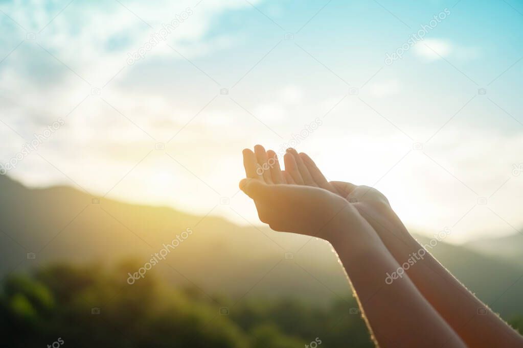 Woman hands place together like praying in front of nature green bokeh and blue sky  background.