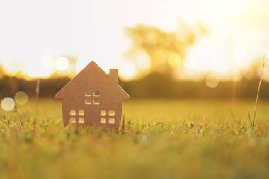 Güneş ışığı arka plan ile yeşil çim üzerinde küçük ev modeli kapalı.