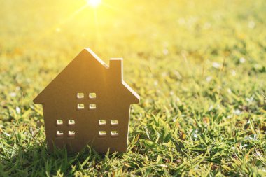 Güneş ışığı arka plan ile yeşil çim üzerinde küçük ev modeli kapalı.