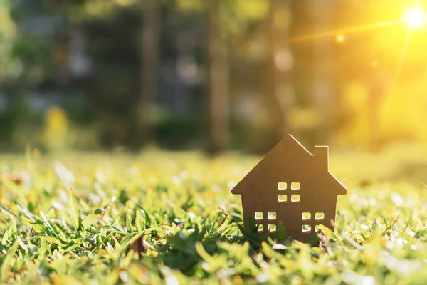 Güneş ışığı arka plan ile yeşil çim üzerinde küçük ev modeli kapalı.