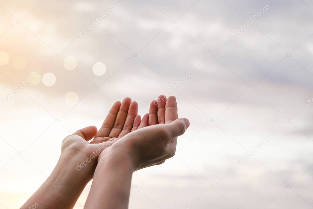 Woman hands place together like praying in front of nature blur beach sunset sky background.