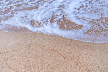 Kum ve suyun en üst manzarası temiz plaj ve yazın beyaz kum, açık mavi gökyüzü ve soyut arkaplan.