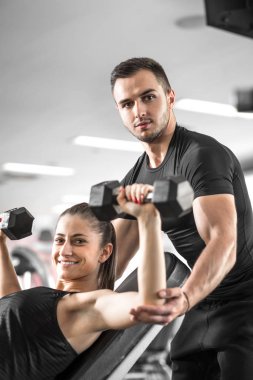 Kadın fitness antrenör yardımıyla yapıyor.