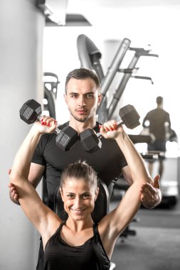 Kadın fitness antrenör yardımıyla yapıyor.