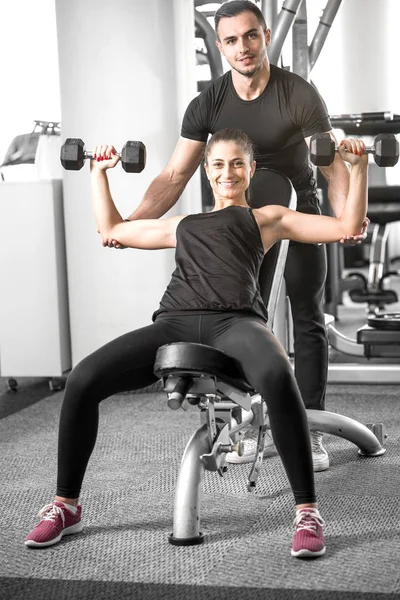 Vrouw doet fitness met persoonlijke trainer help. — Stockfoto