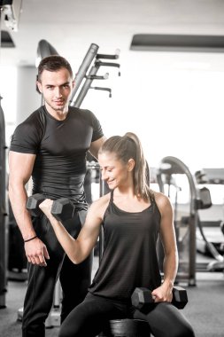 Onun kişisel antrenör ile spor salonunda pazı bukleler yapıyor kadın