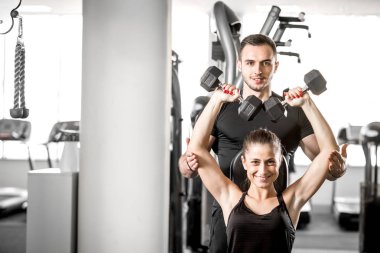 Kadın fitness antrenör yardımıyla yapıyor.