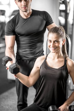 Onun kişisel antrenör ile spor salonunda pazı bukleler yapıyor kadın