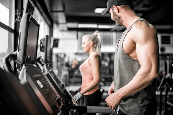 Attractive man running on treadmill and looking at girl — Stock Photo, Image
