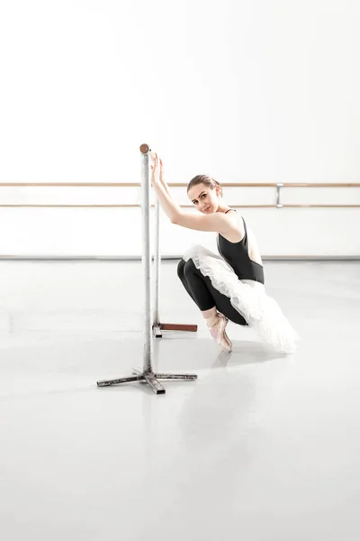 Bellerina, táhnoucí se v baletní studio s barem — Stock fotografie