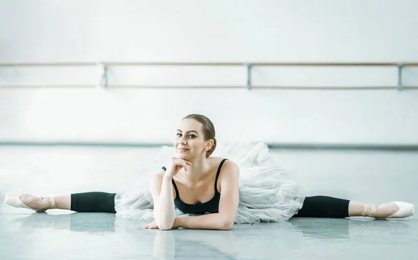 Bellerina dělá noha na podlaze v baletní studio — Stock fotografie