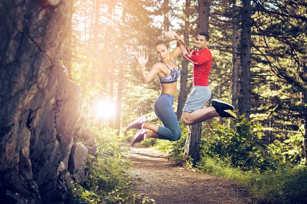 Fitness paar springen in bos. — Stockfoto