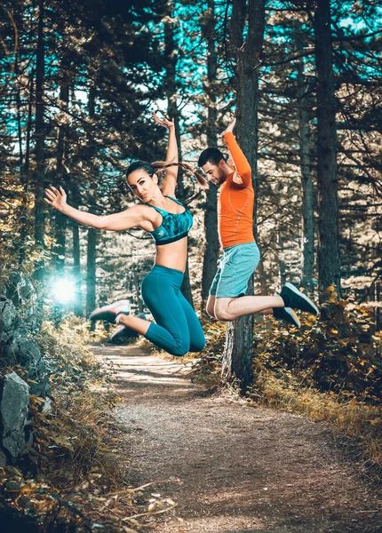 Fitness paar springen in bos. — Stockfoto