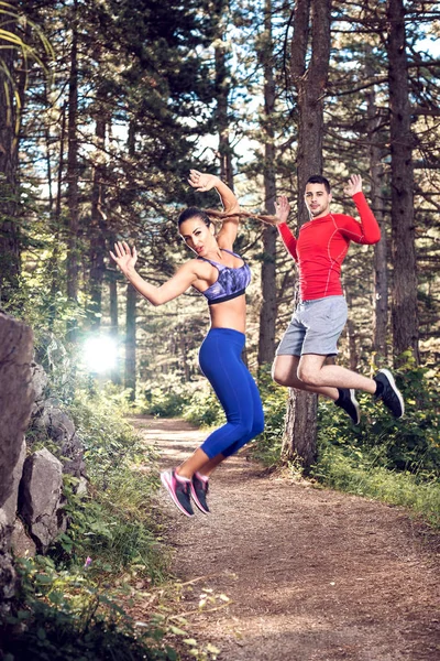 Fitness pareja saltando en el bosque . — Foto de Stock