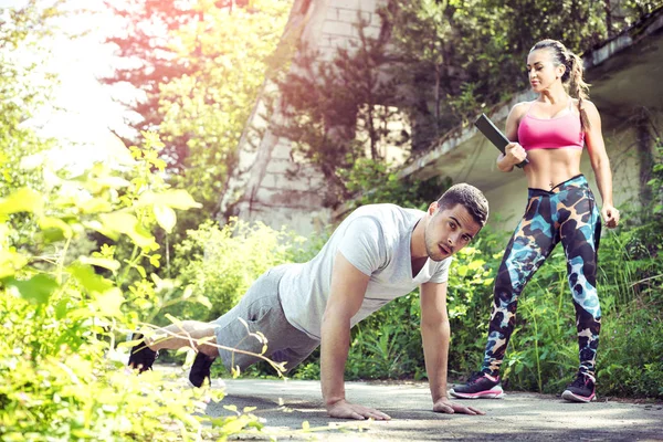 Femmina personal trainer e il suo cliente facendo push up all'aperto — Foto Stock