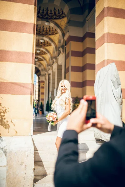 Жених фотографирует свою невесту на смартфоне — стоковое фото
