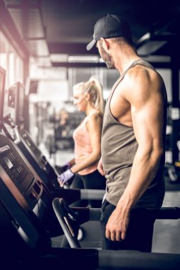 Koşu bandı üzerinde çalışan ve kıza baktığını çekici adam