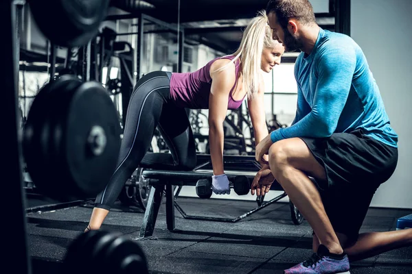 stock image Personal trainer helps his client during row exercise.