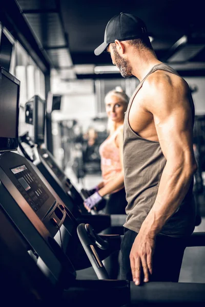 Attractive man running on treadmill and looking at girl — Stock Photo, Image