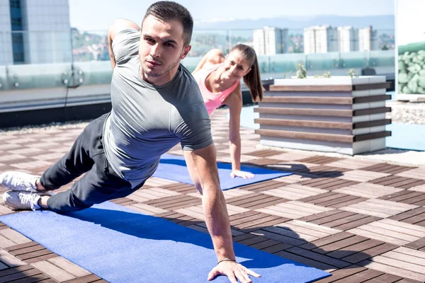 Couple doing side plank exercise.