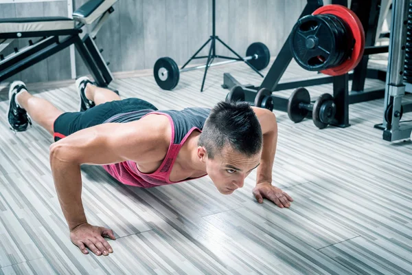 Young man doing push-ups in gym — Stock Photo, Image