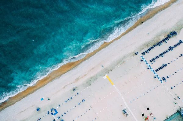 Bovenaanzicht van natuurlijke helderblauwe zee en wit zandstrand met parasol — Stockfoto