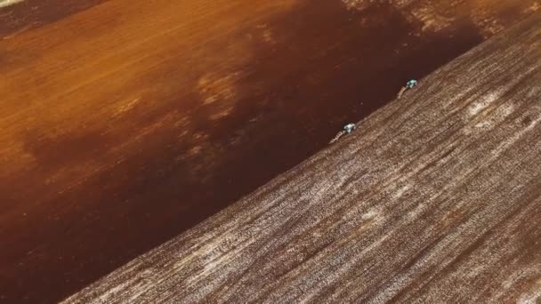 Удивительный вид с воздуха на трактор, возделывающий заснеженное поле зимой. 4k — стоковое видео