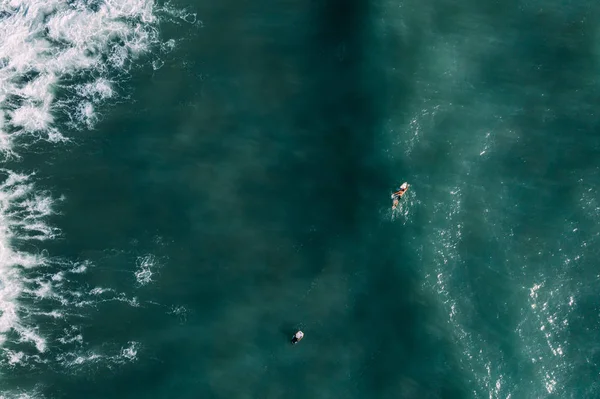 Vista aérea de los surfistas esperando, remando y disfrutando de las olas en un hermoso agua azul — Foto de Stock