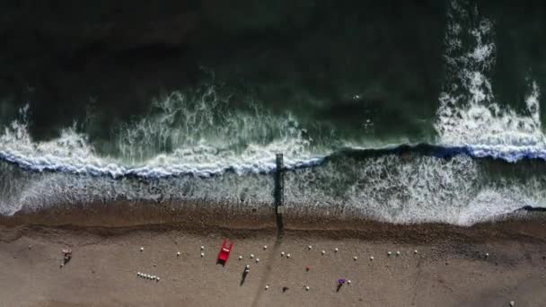 砂浜の海岸線で波が打ち寄せる。深い青い海の水と泡の波を満たす黄金のビーチの空中ショット. — ストック動画