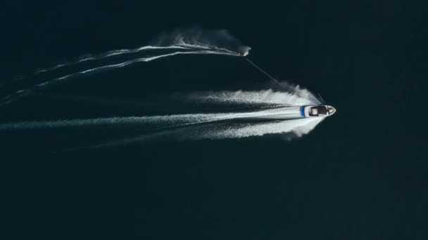 Aerial footage of a speed boat pulling a wakeboarder on a calm sea — Vídeo de Stock