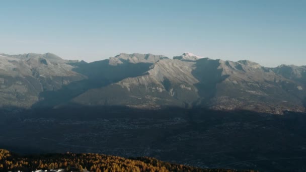 Flying over a city surrounded by mountains and autumn forest. — Stock video